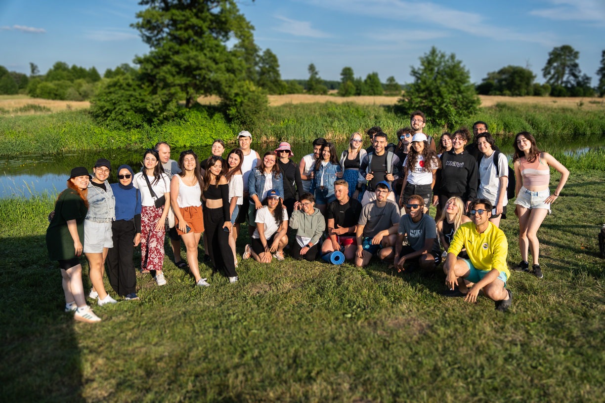 Grupa studentów pozuje na brzegu rzeki przed spływem.